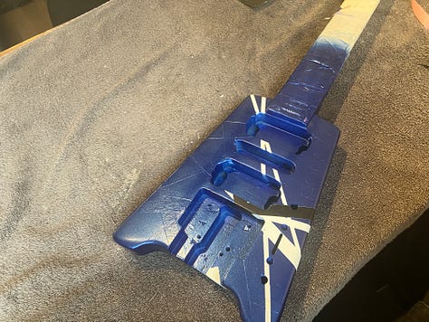 An image gallery showing a headless guitar being stripped down, sanded, repainted, and reassembled. By the end, it's blue with black and white stripes, and looks extremely shiny.