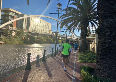 Canal on the left of the path, runners ahead on the course