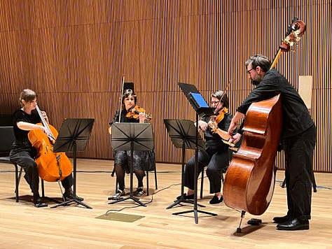 Musicians with classical instruments in a performance space.