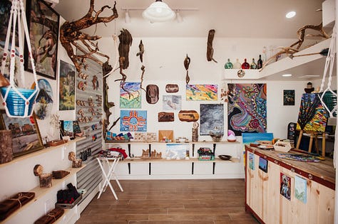 artwork depicting southwest plants and imagery hung salon style on white walls in a gallery.
