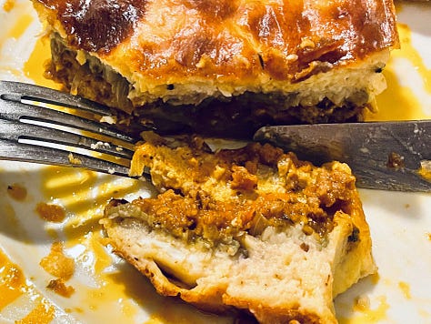 Close-up of a serving of Moussaka, showcasing its creamy béchamel topping and flavorful layers of eggplant, meat, and spices.