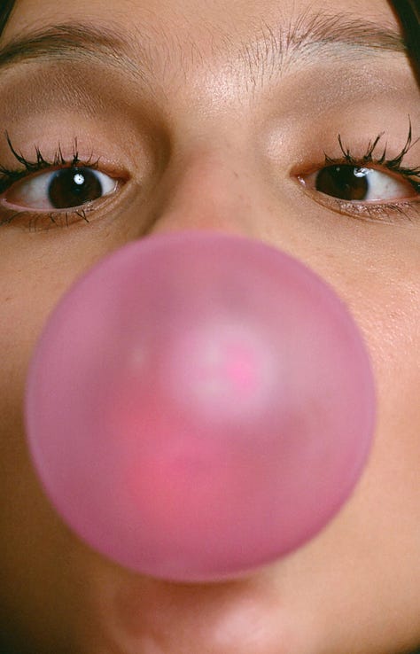 1: A pair of over the ear, wired headphones atop a blue sky with a cloud. The bottom text reads in an all-caps: “Choose your escape route.” 2: A close up of Olivia Rodrigo’s face, only her eyes and eyebrows are visible. She’s blowing bubblegum. The large, pink circular bubble obscures the singer’s nose and mouth. Her eyes focused the pubble at the center of the image. 3: Repeated black and white photograph of a couple kissing. 4: Black text in a techno-esque font on a white background reads “outside the party inside the dream.” 5: Photograph of a tarp printed with an image of a blue sky with white clouds. Two slits at the bottom of the tarp allow three children to peek through the tarp. 6: Screenshot of the comment section of a Tik Tok video. Green trees are visible in the top of the image, above the open comment section. The comment section is a white box that takes up the majority of the image. Tik Tok user danica comments “what aesthetic is this ? x.” Tik Tok user marinersarchive responds “walking outside.” The original commenter, danica, responds “Thank you!” 7: Illustration of a person with dark hair sitting face down in a bathtub surrounded by photographs of men who look like pop idols. A can with cigarette butts and a smartphone sit on the edge of the bathtub. 8: A young teenager sitting on a bike looks over her shoulder directly at the camera. She is wearing a flower crown, a costume elf ear, and her face is painted with a pink flower. 9: A soft photograph of daisies blurred, as if in motion, against a light blue background. 