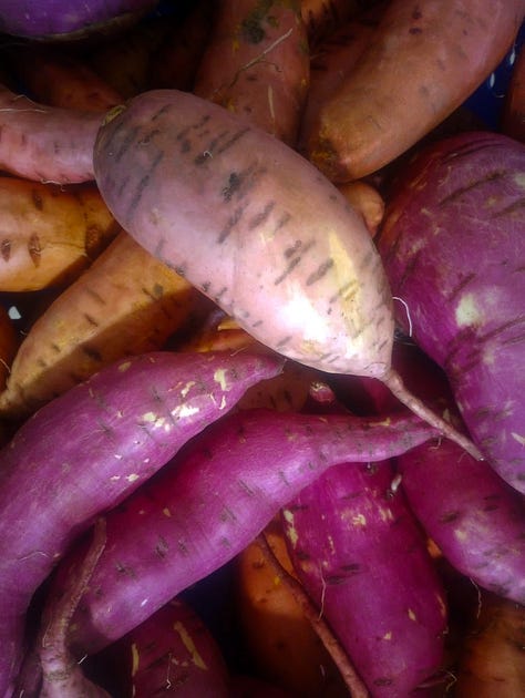 A close up of a pile of purple and orange sweet potatoes.