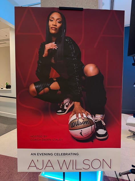 Me and A'ja's statue; custom art of A'ja; Dawn Staley, the artist of the painting shown, and A'ja; poster from the event I attended; A'ja decal on the arena; me and Janel; posing in my A'One shirt; A'ja's retired jersey; Dawn Staley Way