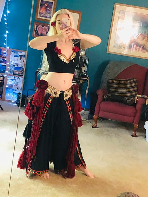 Costume trials in black pants and crop top, with cream and gold belt and bra covered in red tassels and roses. The last photo is one of the roses held in the palm with the red yarn dangles twined around the wrist.