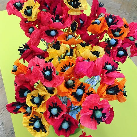 Brightly coloured paper poppies and paper wildflowers arranged in the red and yellow Hillsborough Memorial Banner