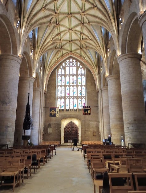 Exterior side of stone building with clock tower, interior with large stained glass window, interior with smaller stanined glass windows, altar, and ceiling decoration that looks like large star, large star, gift shop fll of merch in side chapel, cake slice and cup of tea