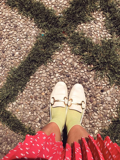 Rebecca wearing a polka-dot dress with a chain belt, yellow socks, and white loafers. Close-up photos of a zip pouch with beaded strawberry details and large red tassel. Interspersed with photos of plants in bloom.
