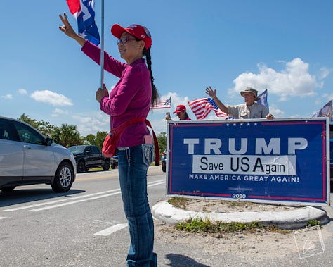 Trump supporters wave flags and signs on a sidewalk in Palm Beach, Florida