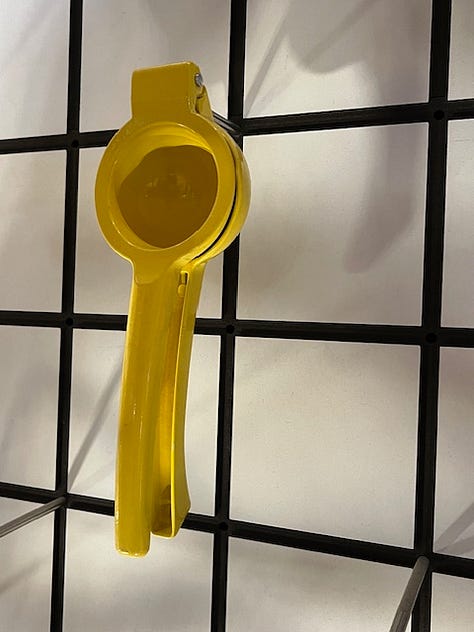 A selection of items on the wall at London's Design Museum including a yellow lemon press, an iconic Phillipe Starck bottle opener, some ice cream scoops, spoons, a hanging wall of classic deisgns and a Chemex pour over glass coffee maker.