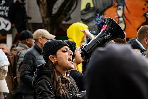 first image: one person is calling out on a megaphone and another just beside is yelling along. i forget exactly what but something to the effect of "fuck the police." second image: person with the megaphone is making snarky comments at a guy with a camera who's been called out by others as being a fascist. i don't know who the guy is who was being called a fascist or his name. last image: VANDU organizer Vince Tao on the microphone