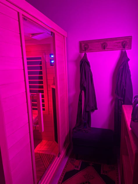 9 images in a gallery: an infrared sauna lit pink, luminaries on a snowy street at dusk, a candle and legs crossed on a yoga mat, a 3 year old boy in a blue coat plays in the snow, a 40 year old windswept woman walks by lake michigan and a red lighthouse, seasonal hand cream and chapstick, a seasonal soup in a red enamel pot, hot chocolate with marshmallows, and a cozy massage table