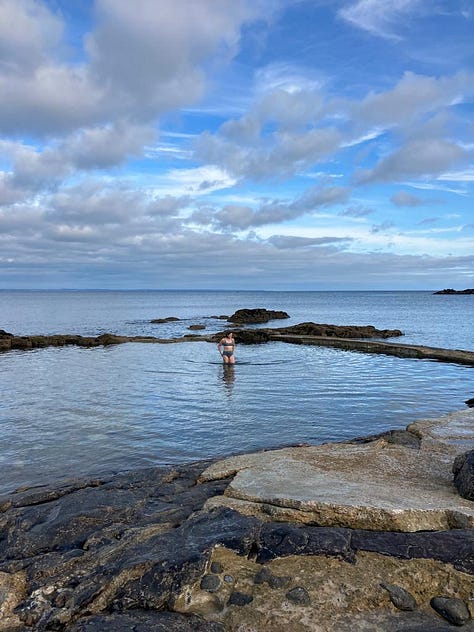 Woman with her feet in the water, woman looking out to sea, woman in the water.