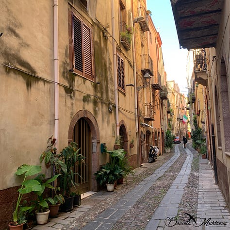 Three narrow streets in Bosa with plants decorating the entrances and streets