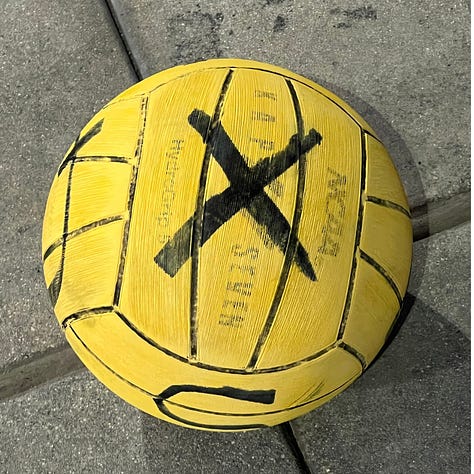 Water polo balls with bold black letters written on each face. The letters are X, Y, and S