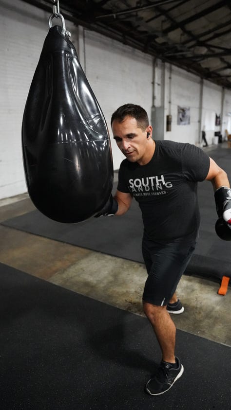 Brian hitting a punching bag at the back of a gym.