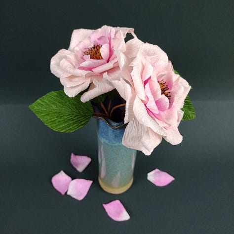 Three images of the new open Rose CraftKits showing the contents of the kit, paper, wire and instructions, plus the finished roses, very pale pink with a darker pink centre, a dark brown stem and deep green leaves.