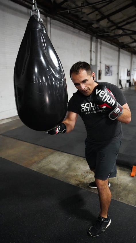 Brian hitting a punching bag at the back of a gym.