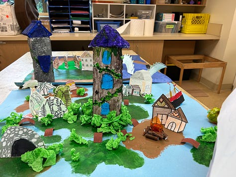 Square cardboard maps are decorated with paint, carved styrofoam, cardboard towers and paper cutouts to depict fantasy environments.