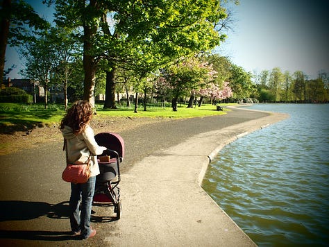 Woman with pram in a park beside a pond and a cat beside a black and white print of a happy couple. A woman on a picnic blanket with a baby in a garden