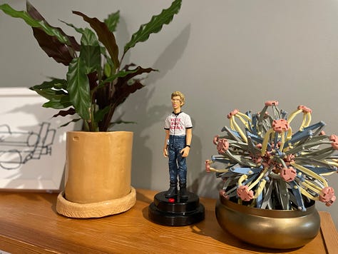 Top left: A shelf with my Napoleon Dynamite figurine, a plant pot I made in a recent pottery class, a fidget toy in a brass coloured dish. Top middle: a frozen pizza inside a box (my son's safe food). Top right: Taskmaster on TV with a packet of prawn cocktail crisps in my hand. Middle left: Toby, my one year old seal point Ragdoll. Middle middle: Harry, my two year old blue point Ragdoll. Middle right: a Monarch butterfly I photographed whilst hanging out laundry. Bottom left: My spider plants with lots of tiny spiderlings! Bottom middle: my watch displaying a sunny local weather forecast. Bottom right: a reupholstery project I have completed this week.