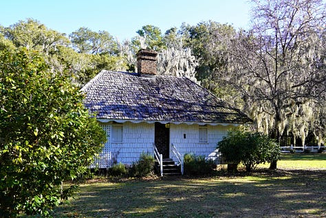 A small white building with a shingle roof that is the slave quarters at Hopsewee. Second and third photos show the large brick center fireplace.