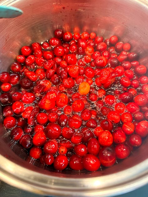 cranberries in a sauce pan cooking and then canned ready for Thanksgiving