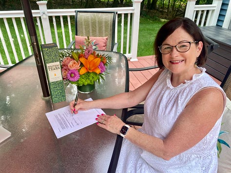 Woman signing book contract, two hands toasting, two women holding a bottle of writers tears