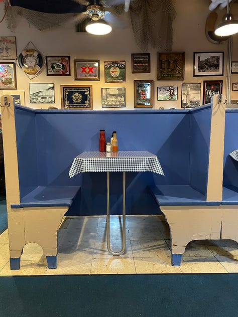 Inside Emmett's Oyster Bar in Seattle. Blue and white checkered table cloths, oysters, interior signage, and a sleeping dog. 