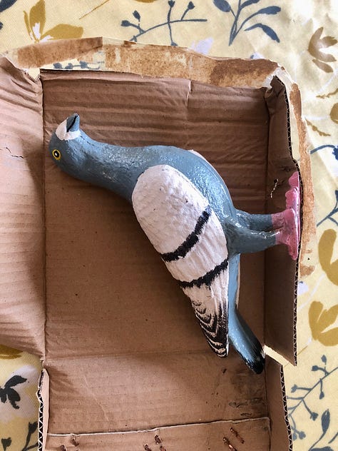 Photos showing a cast iron figure pigeon coming out of a cardboard box