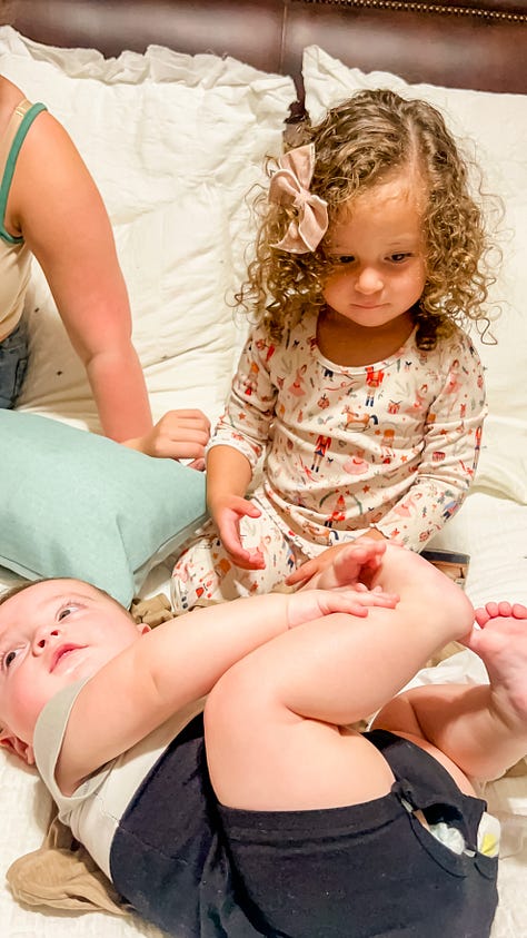 Photo of woman carrying baby boy in her lap with her grandma holding baby's hand; toddler playing with her baby brother on a bed; toddler playing with a bunny rabbit who peeks out from underneath a bed; Two women standing posing at a graduation party in front of a table with a cake, balloons and gifts; a 2-3 foot sized pan of rice with chicken and vegetables; view from a driver's side window of a horse and carriage on the side of a tree-lined neighborhood street; a water bottle with stickers and placeholders for stickers of U.S. National Parks; a photo of a desk with journal, photos, a camera, laptop and other items strewn about; a photo of a cloudy sky where the sky looks like bunches of cotton balls, with the tops of palm trees and city buildings in the latter half.