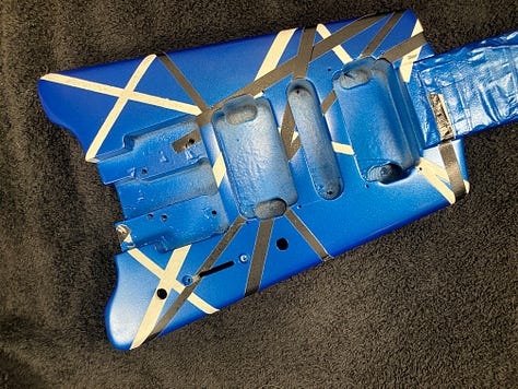 An image gallery showing a headless guitar being stripped down, sanded, repainted, and reassembled. By the end, it's blue with black and white stripes, and looks extremely shiny.