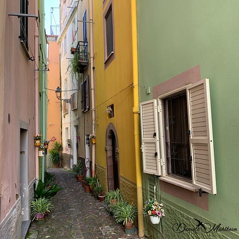 Three narrow streets in Bosa with plants decorating the entrances and streets