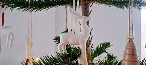 Six photos of stag decorations. 1. cushion with stag head; 2.  2 small black wooden deer ornaments; picture in frame of stag against blue background with message 'Season's Greetings'; white wooden stag figure; two silver stags facing each other with their antlers as candleabra; delicate white ceramic stag tree decoration.