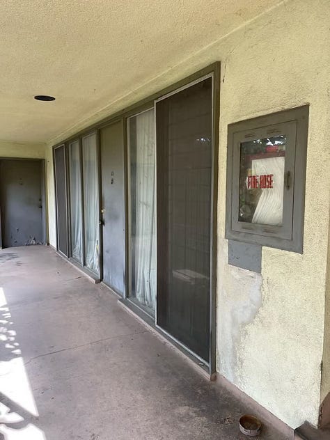 2040 Rodney Avenue, a midcentury modern apartment complex that has been empty for years and is suffering from deferred maintenance (mold, stucco damage, peeling paint, a long-empty pool, cracked concrete, rust stains, etc.).