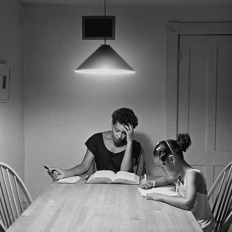 1-9) All images are black and white, and involve a table, as well as a few chairs, and an overhead light. 1) A black woman is seen playing cards by herself. 2) A black woman is seen holding her head in her hands, while reading a book. There is a child sitting to her right, writing. 3) A black person is standing at the end of the table, looking into the camera. 4) A black woman is looking at herself in a tabletop mirror, while a child is playing to the right of her at the table. 5) Three people are sitting at the table, and appear to be playing a game or laughing. 6) A black woman is seen looking at herself in a tabletop mirror. 7) A black woman is sitting on the left side of the table, with her hand under her chin. There is a black man at the end of the table, reading the newspaper, with his hand resting on his neck. 8) Two black people are seen kissing/embracing. One is sitting at the end of the table, and the other person is behind them. 9) A black woman is seen with her head laying back on the table, with her hands in her hair.