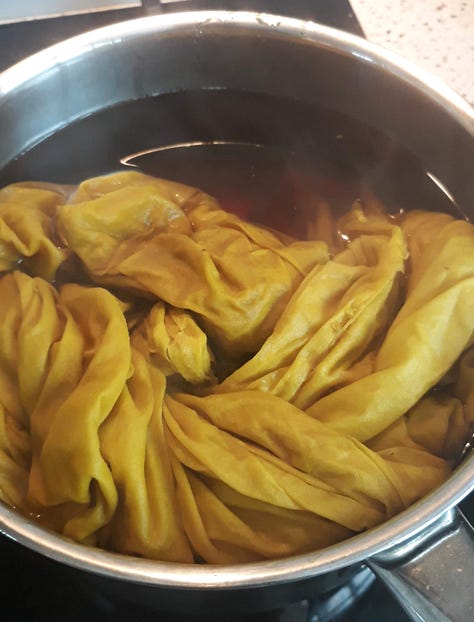 The marigolds bright orange in the pot, the white fabric lowered into the pot and dyed bright orange, the fabric after being fully submerged with a final mustardy yellow result