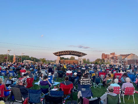 people sitting in lawn chairs or dancing at a concert