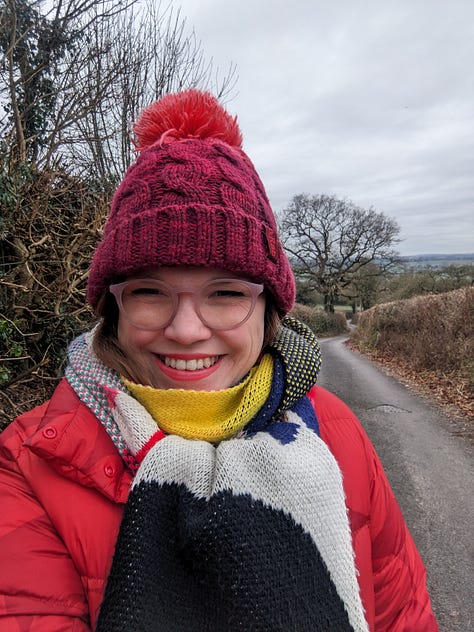 A series of images of the Somerset countryside in the winter. From top left: fields in the frost with a sunrise on the horizon, a country lane with a tree at the bottom and fields in the distance and a sunrise sky, a river bordered by trees and frosty fields, Libby Page smiling at the camera while out on a walk wearing a bobble hat, colourful scarf and a red coat, a country lane stretching into the distance, a field of grazing sheep and frosty grass.