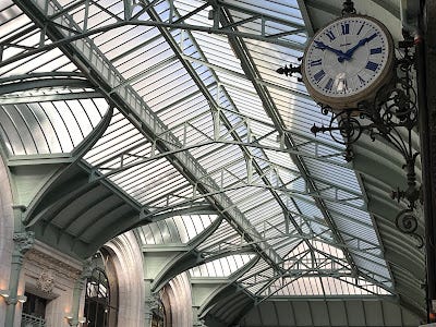 Paris train station entrantrance at Gare de Lyon, a glass and steel girder roof, and hihgoy ornanate images of the decoration in the restaurant.