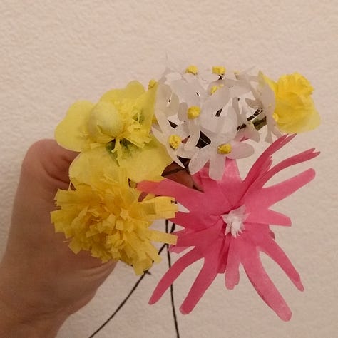 Image one is a hand holding a collection of rather clumsy flowers made from tissue paper, one recognisably a ragged robin, the others yellow and white. Image tow is a hand holding a slightly more refined bunch of crepe paper flowers, dandelion, plantain, cuckoo flower and grasses. The third image is an elegant stem of pure white meadow cranesbill, made of paper