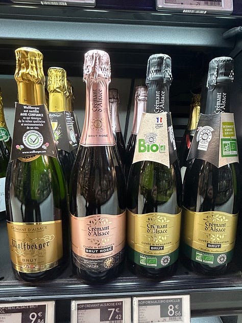 Bottles of different sparkling wines rest on shelves in a French market