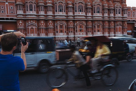 People rushing in the foreground of the Hawa Mahal.