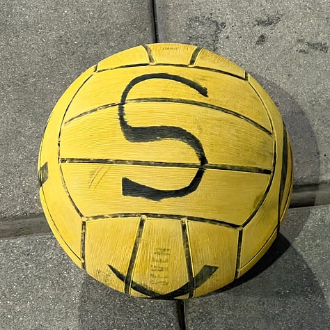 Water polo balls with bold black letters written on each face. The letters are X, Y, and S