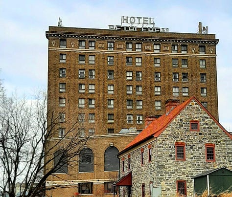 A collage of photos showing the Historic Hotel Bethlehem, including two photos of the 9-story brick exterior, and interior pictures of the elevators, white marble staircase with polished handrail, open doors to the ballroom with a glistening chandelier, and two photos of the lobby, with luxurious black leather furniture in front of a huge arched window with a Christmas wreath in the middle. Also a look inside a room of a bed with a robe lying on the end.