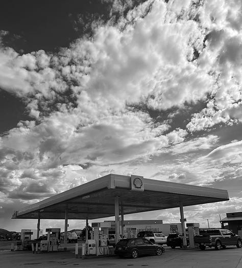 Gas station with clouds in the sky, the flat desert, and an old-school phone booth 