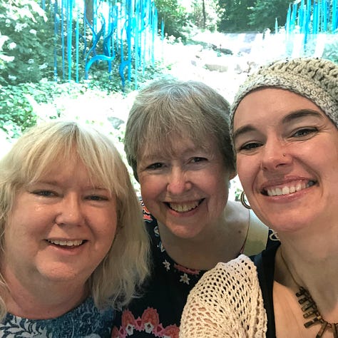 The author with her mother--both grinning huge in front of the flag at Fourth of July; mom dressed as Jack Skellington in a Santa hat playing the piano; three smiling women with similar faces in front of the turquoise Chihuly blown glass reeds.