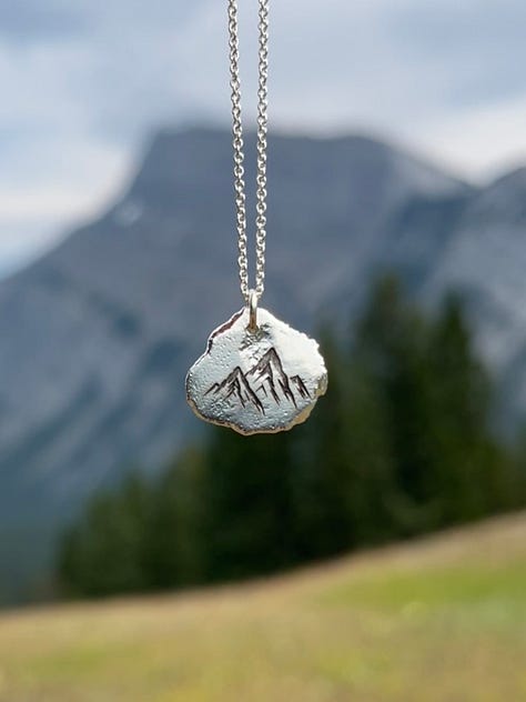 Image 1: Acrylic "Inspired by Nature" ornament engraved Bear with cub. Image 2: Acrylic Embryo engraved ornament. Image 3: "Inspired by Nature" Silver Nugget with Mountains Pendent with silver necklace. Image 4: Acrylic engraved "Our Cubs" ornament placed on a Christmas tree. Image 5: Silver Nugget Pendent "Sand Dollar" with silver necklace. Image 6: Silver Nugget Pendent "Daisy" with silver necklace.