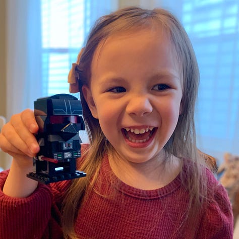 My daughter, Hannah, enjoying Star Wars Golden books, and Darth Vader Legos