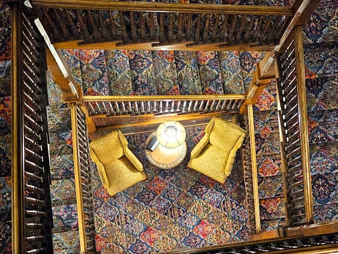 The historic central staircase at Mohonk with wooden spindles and colorful carpet.